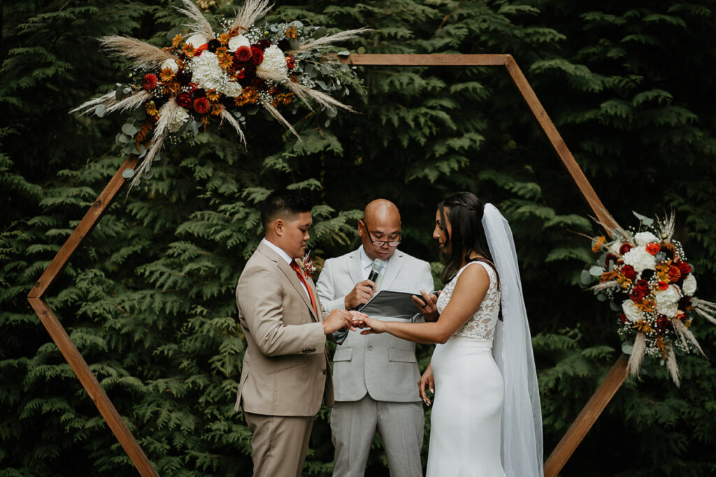 One of the brides putting a ring on her new wife. 