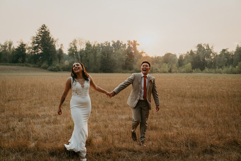 The newlyweds holding hands in a field of grass. 