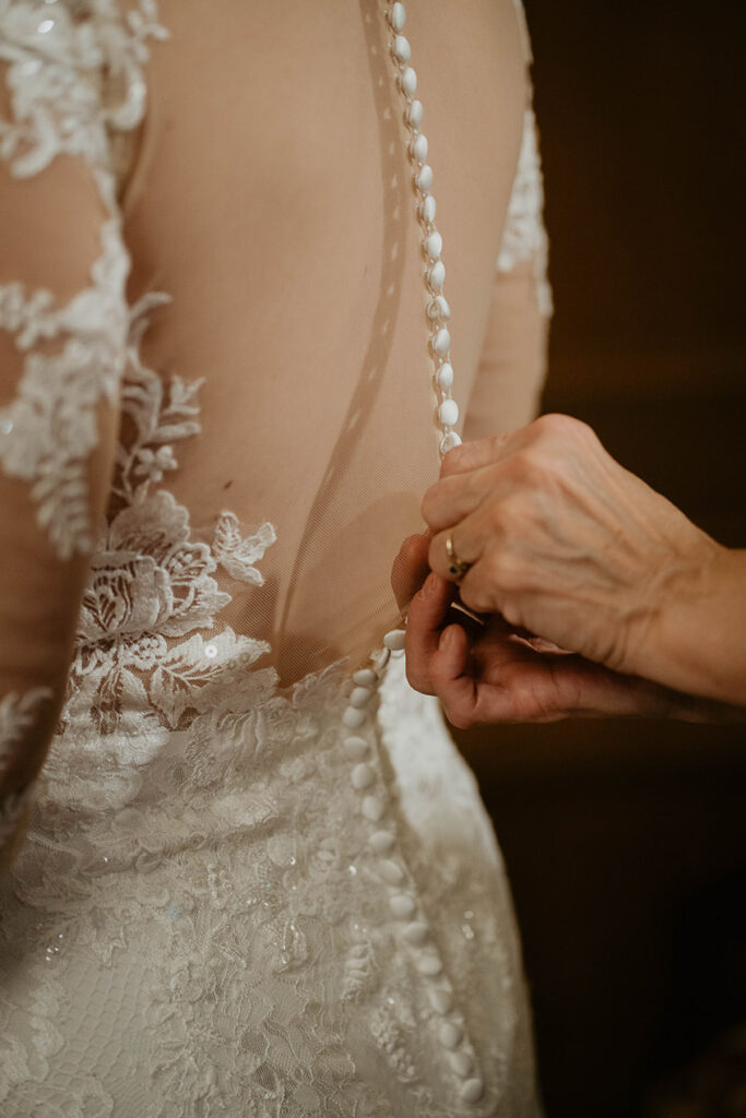 The bride getting finishing touches added to her dress. 