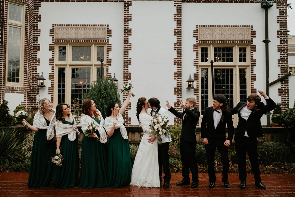 the wedding party cheering on the bride and groom as they kiss. 