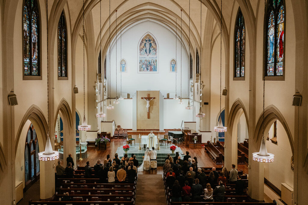 The bride and groom with their guests standing in the Church of the Assumption. 