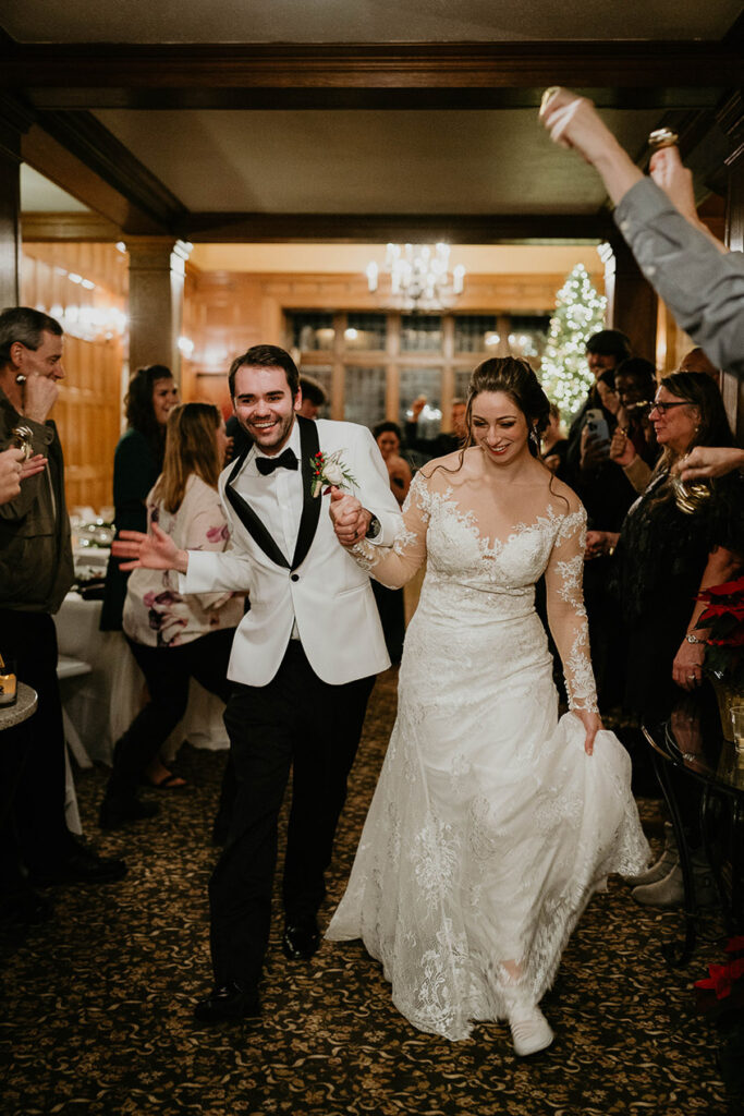 The bride and groom walking out for their grand exit while their wedding guests cheer them on. 