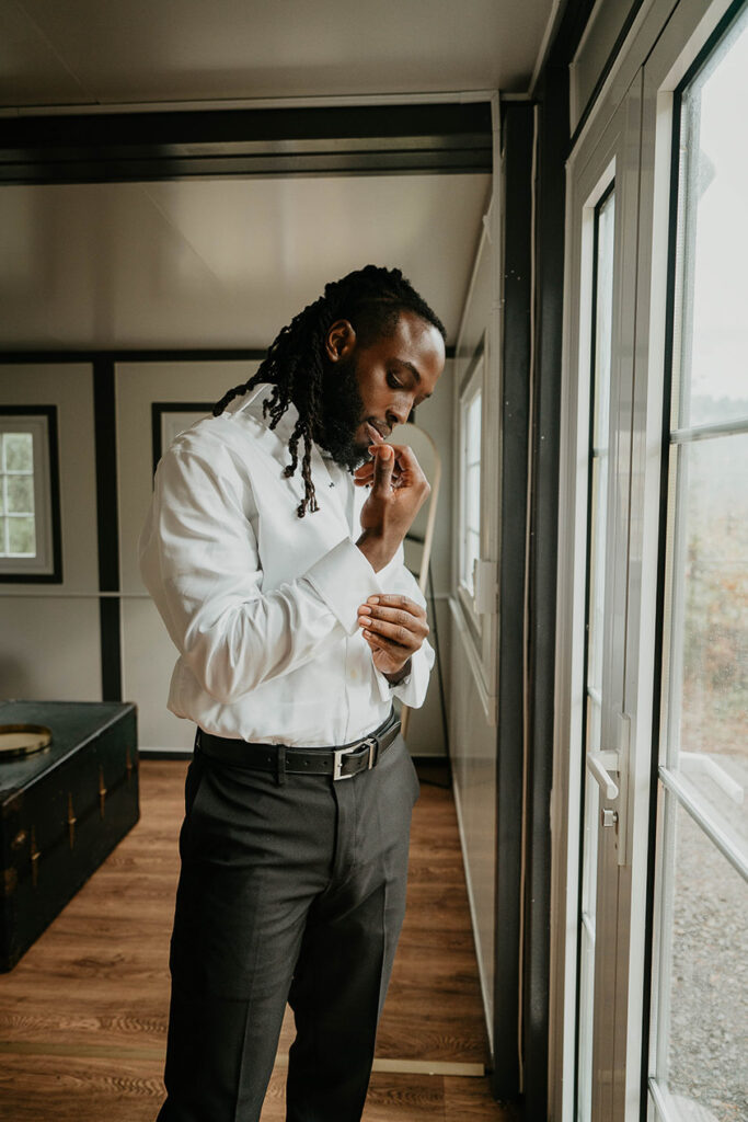 The groom getting ready and adjusting his shirt cuff. 