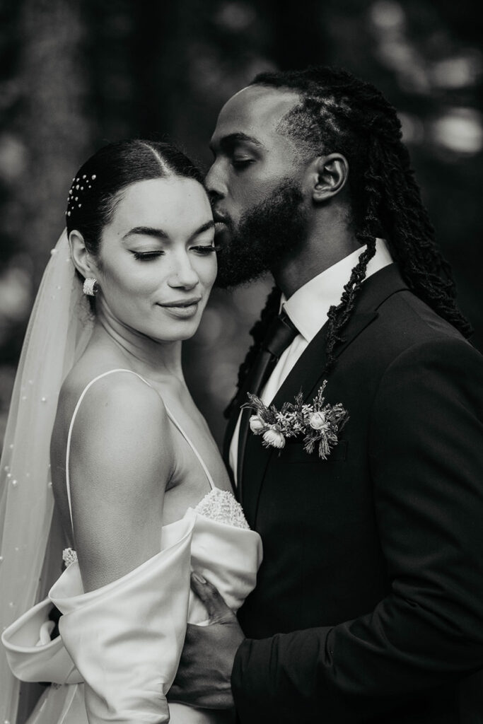 the groom kissing his bride on the side of her forehead. 