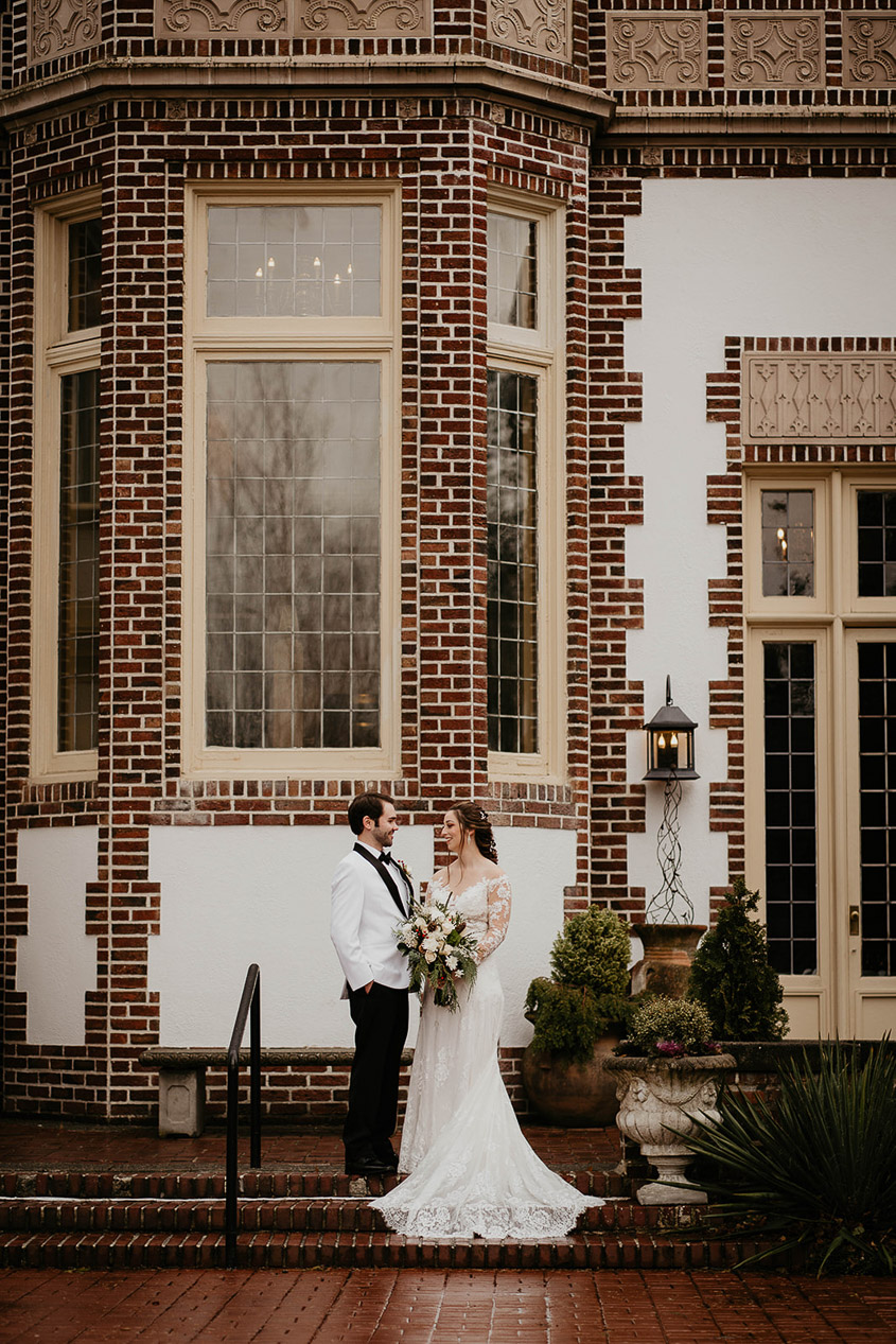 The newlyweds standing in fron to Lairmont Manor and smiling.