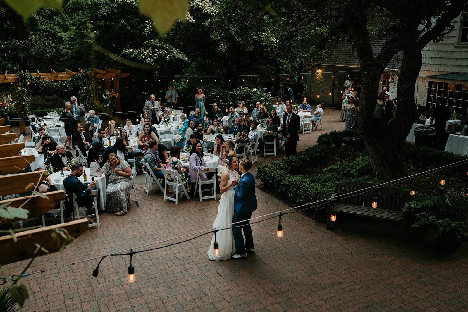 newlyweds dancing on a patio in front of their loved ones at Leach Botanical Garden, one of the best wedding venues in Oregon. 
