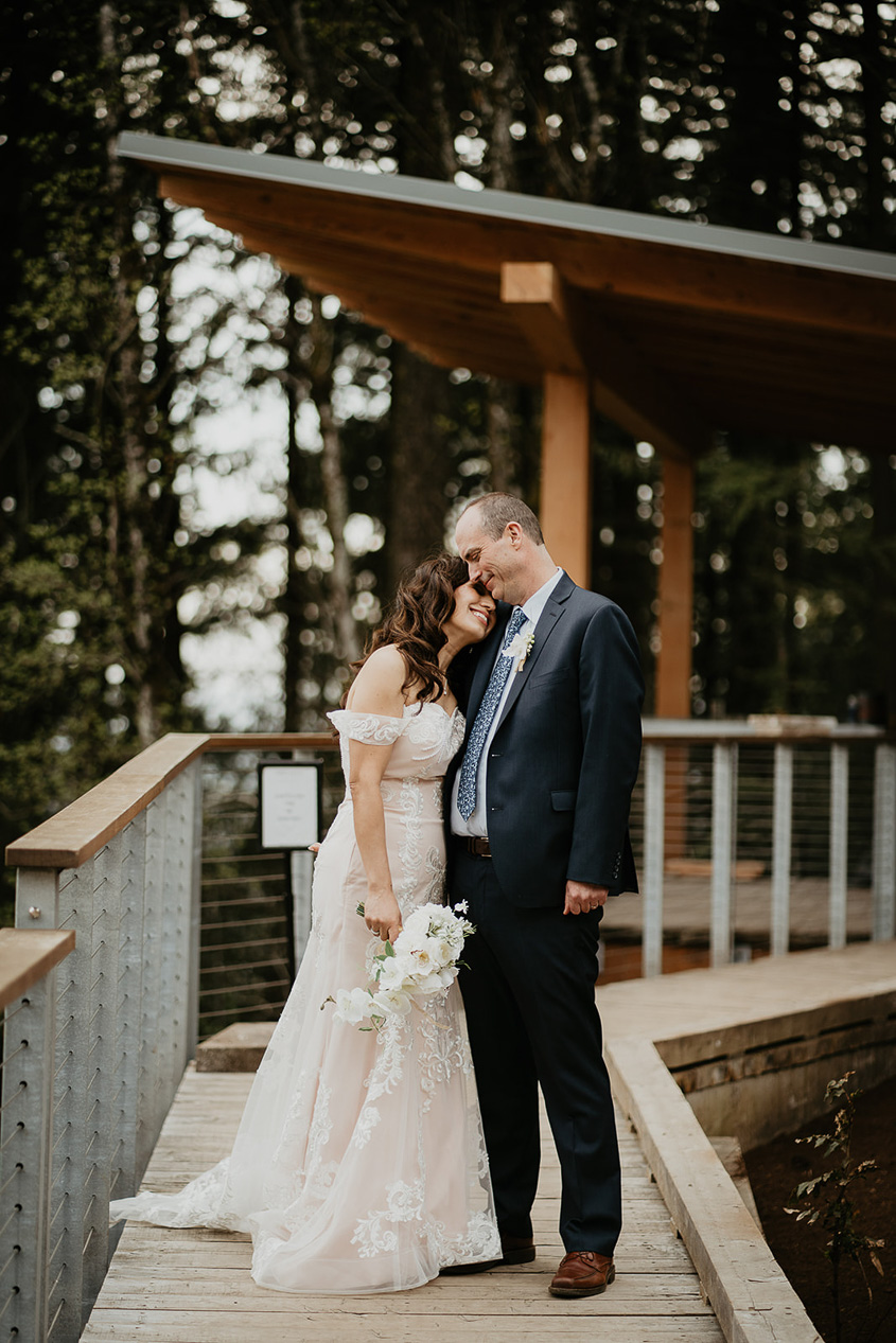 newlyweds hugging on a bridge at Amaterra Vineyards, one of the best wedding venues in Oregon.