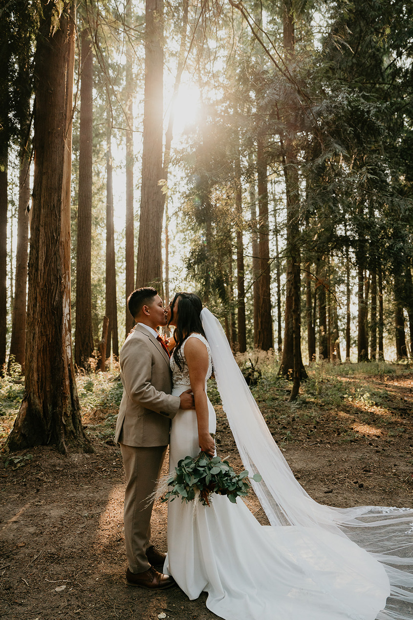 newlyweds kissing in a forest at CedarVale Events, one of the best wedding venues in Oregon.