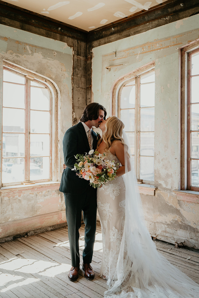 newlyweds kissing in the corner of a decaying building.