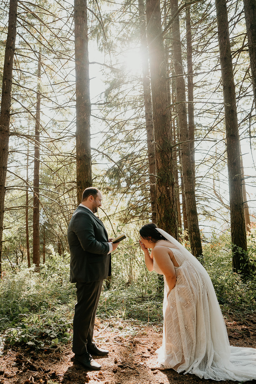 newlyweds sharing a first look in a forest at Wind Mountain Ranch, one of the best wedding venues in Oregon.