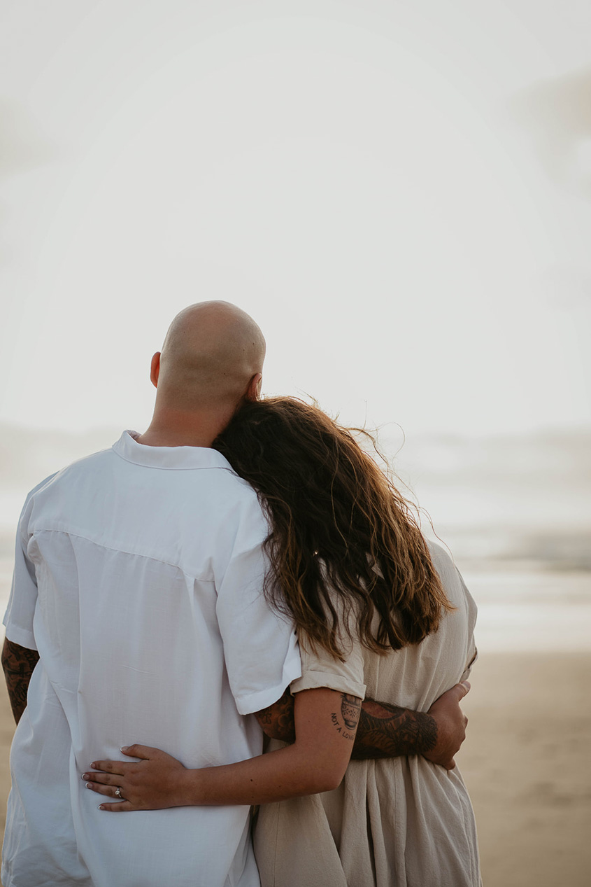 a couple holding each other and looking out over the Pacific Ocean. 