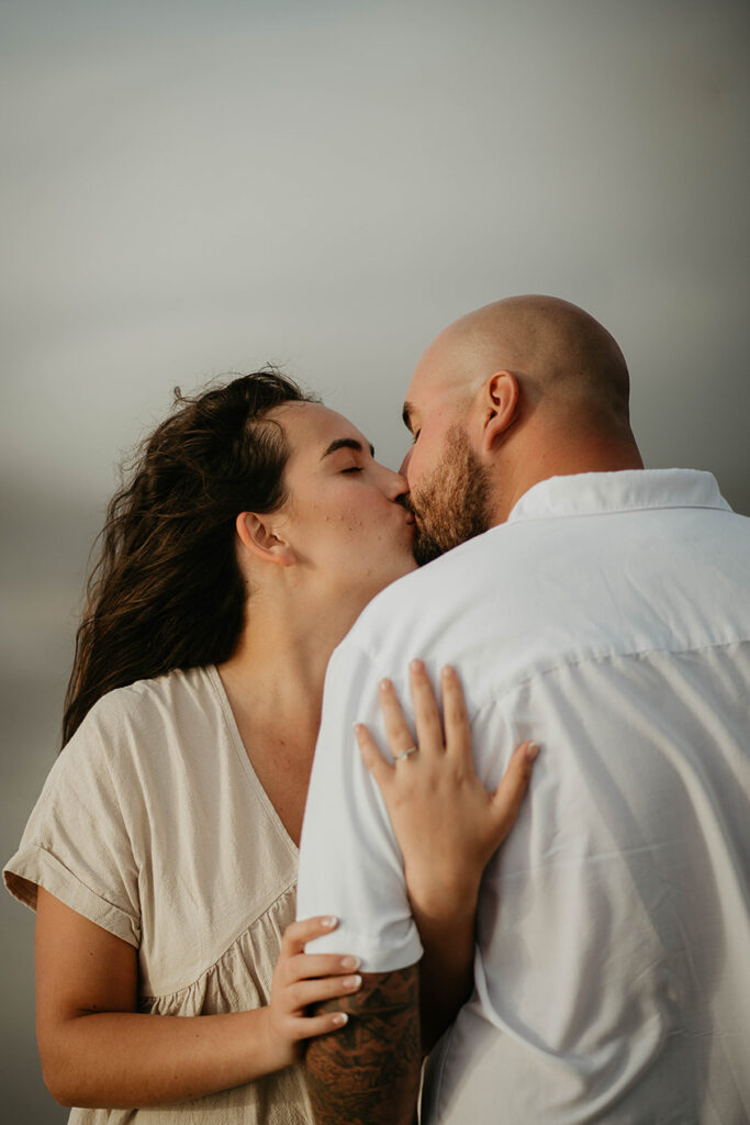 a newly engaged couple kissing. 