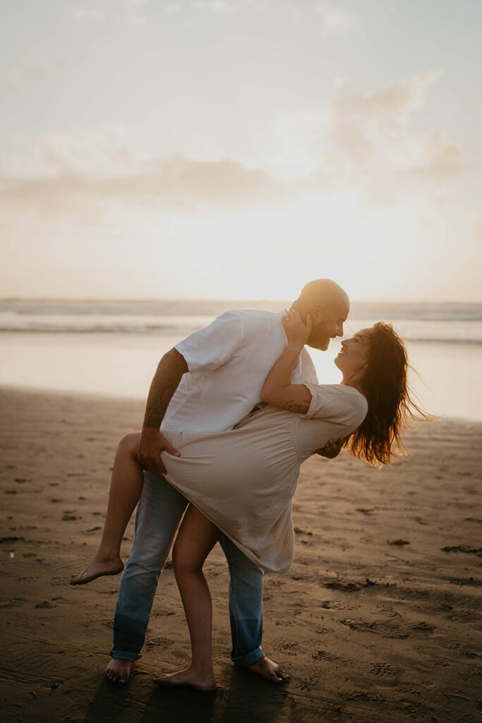 a newly engaged couple kissing as the sun is setting at Cannon Beach. 