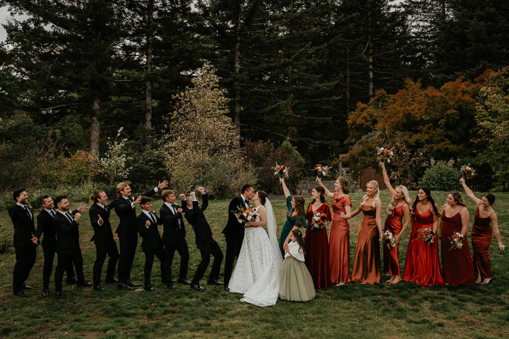 the bride and groom's wedding party on either side of them while they kiss. 