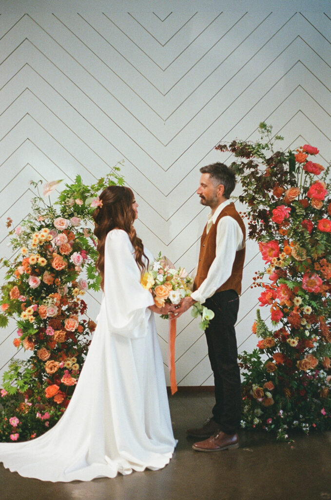 Bride and groom hold hands during their colorful wedding ceremony