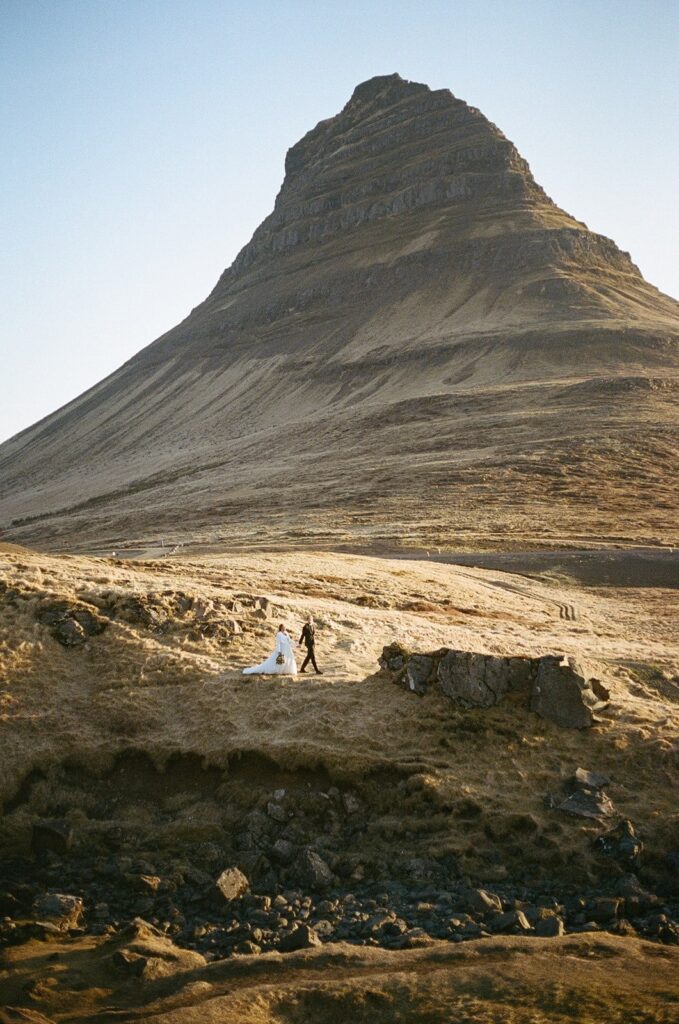 Bride and groom hold hands while walking along a trail in Iceland during their wedding film photography session