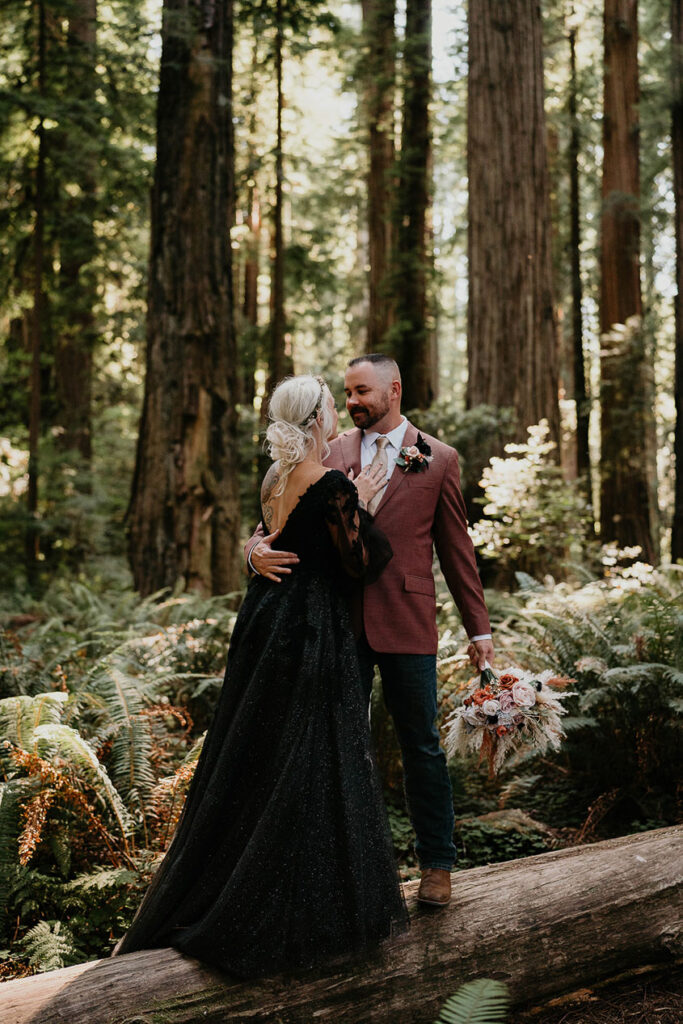 the husband and wife holding each other in the middle of the forest. 