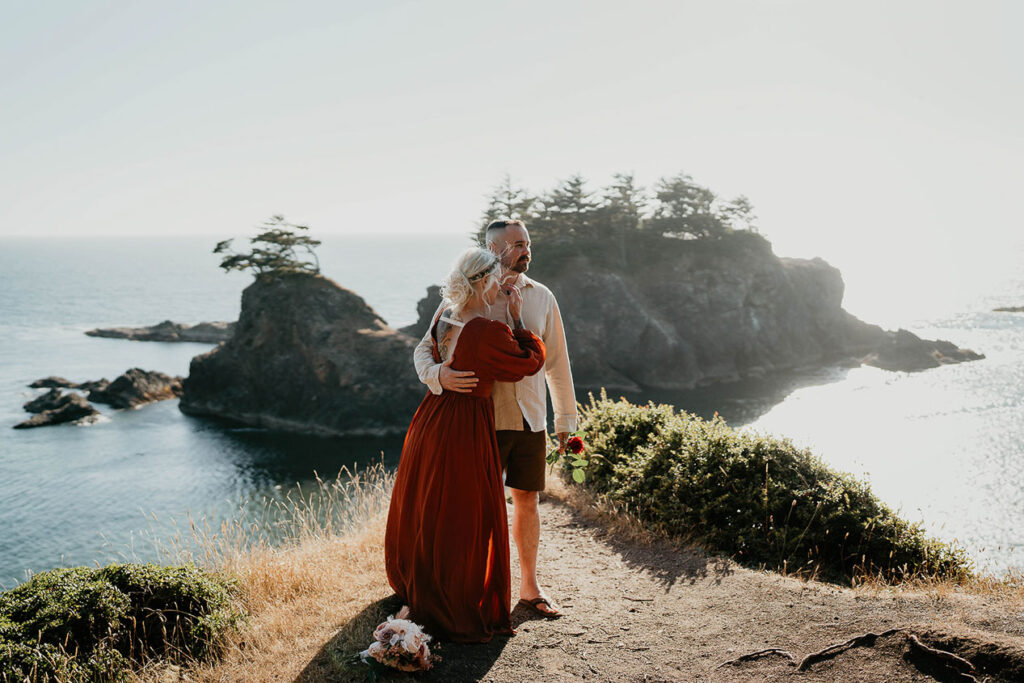 the husband holding his wife with the Oregon coast in the background. 