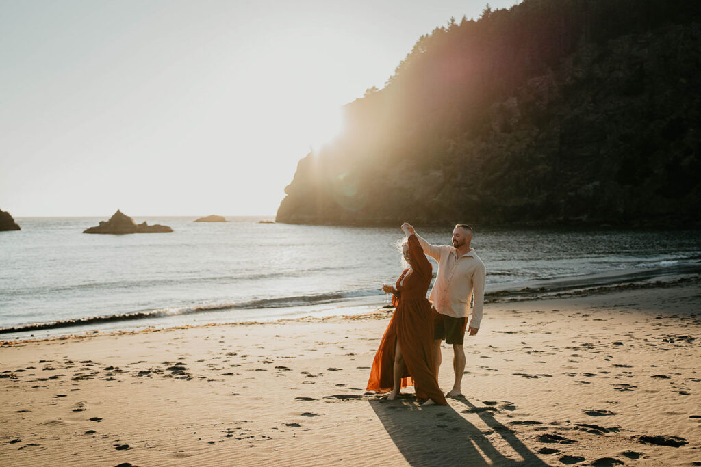 the husband twirling his wife as the sun sets over the Pacific Ocean. 