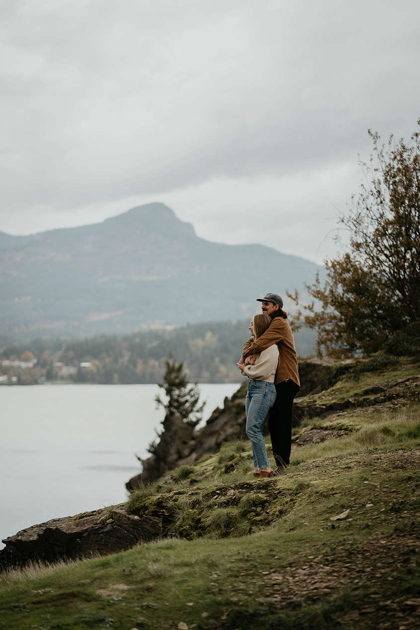 a couple embracing each other on a river bank. 