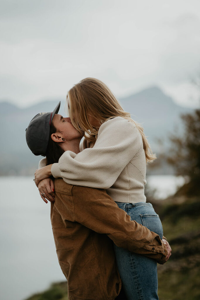 A couple kissing on a river bank. 