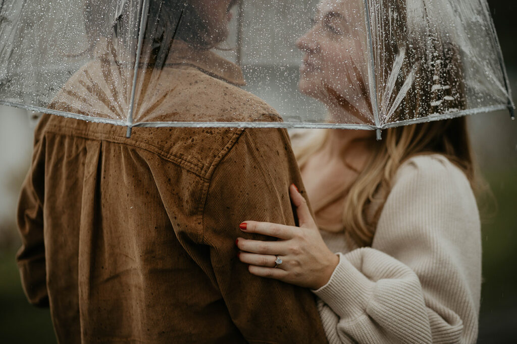 A couple staring lovingly into each other's eyes under an umbrella during a gloomy day at the Columbia River Gorge.