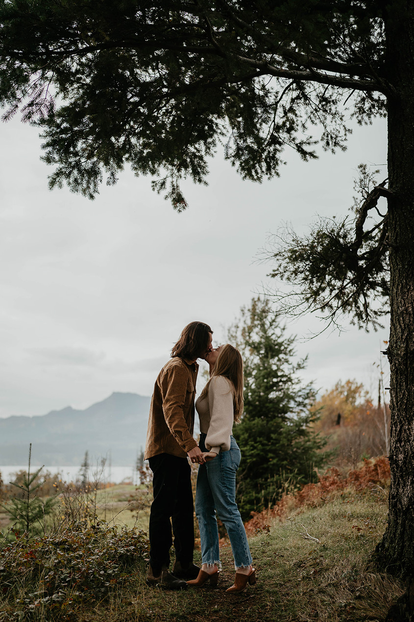 A couple kissing under a tree. 