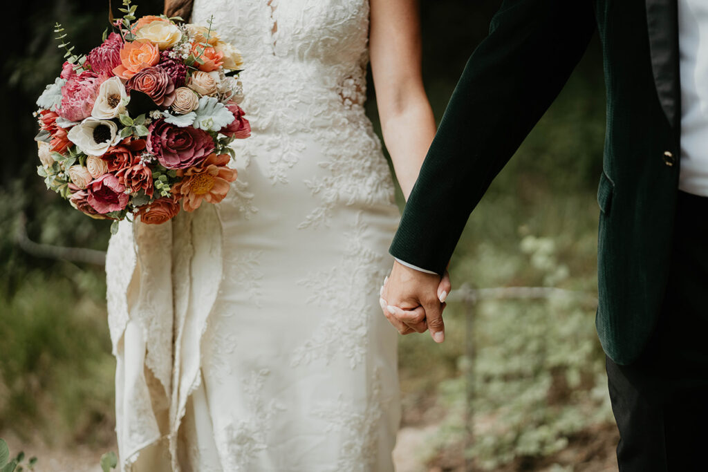 The newlyweds holding hands, with the bride holding a bouquet of flowers. 