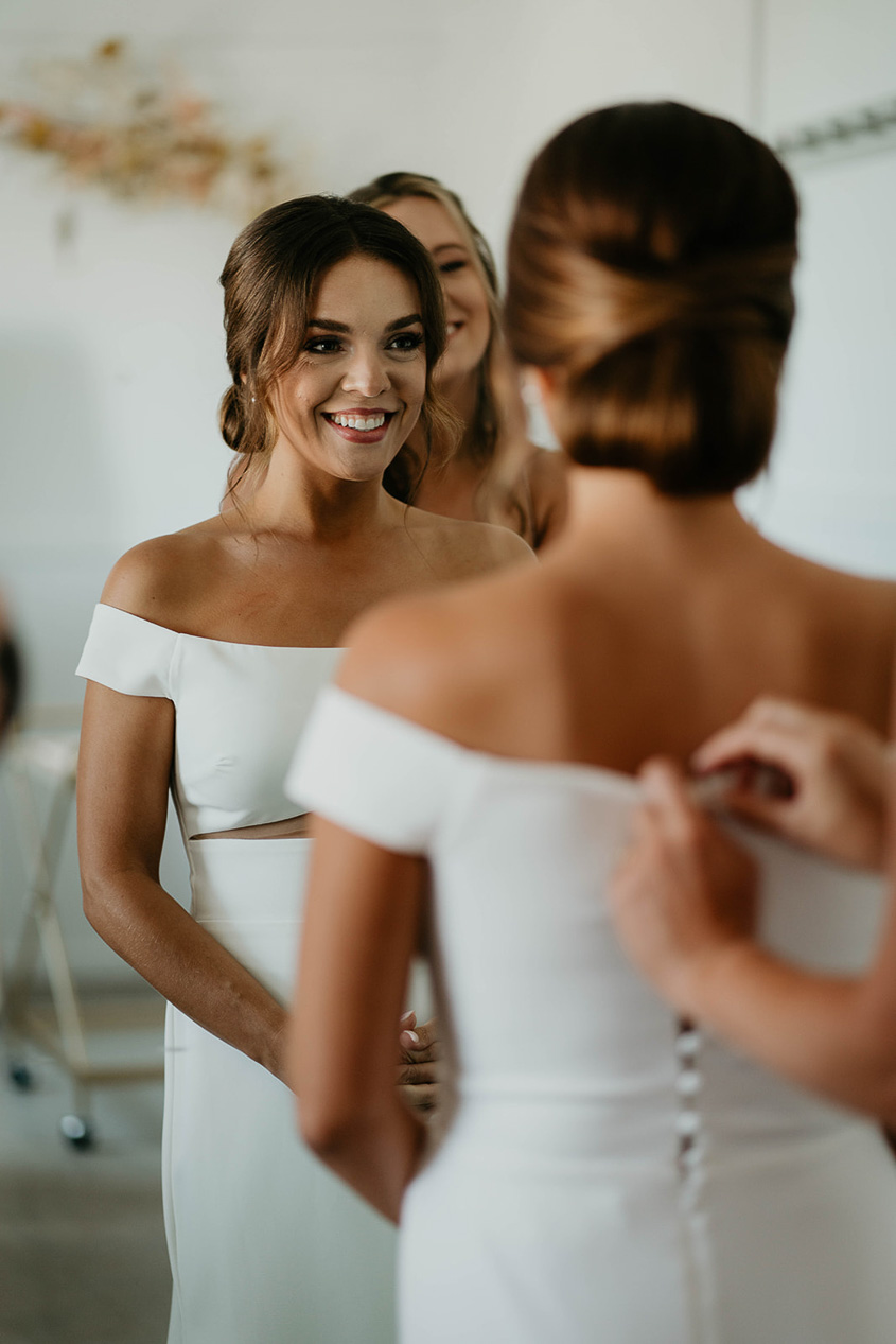 The bride smiling with her bridesmaid's around her. 