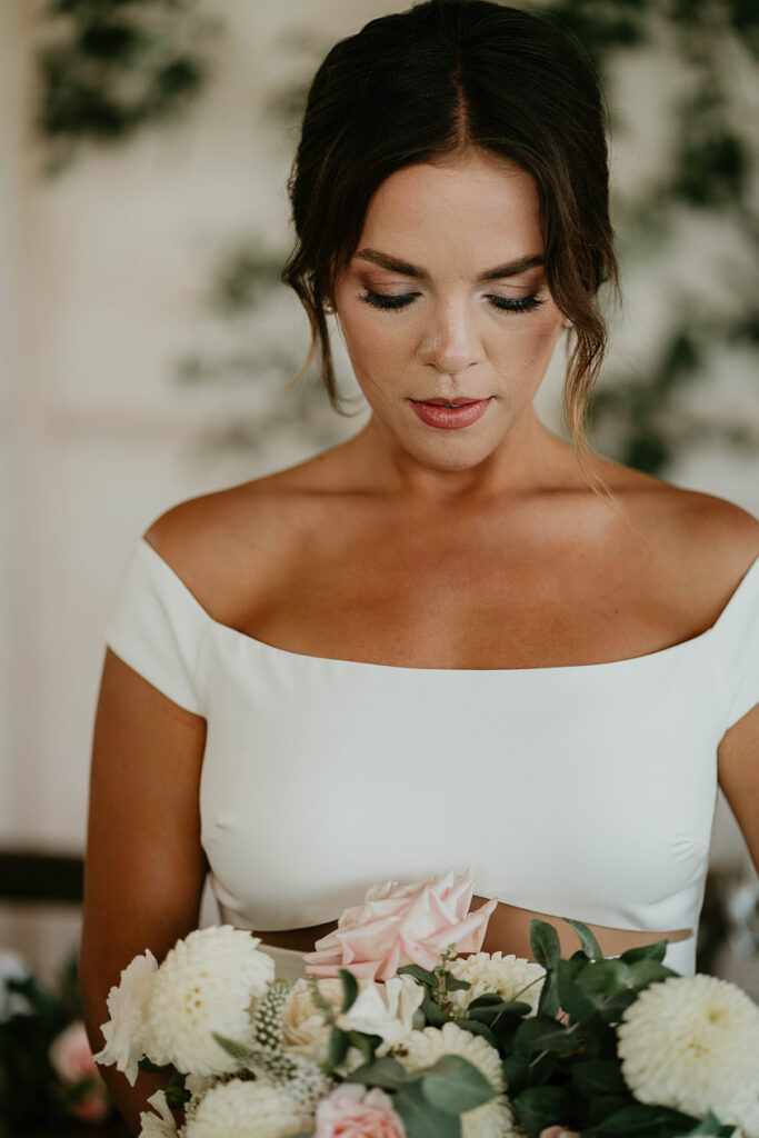 the bride looking down at a bouquet of flowers she's holding. 