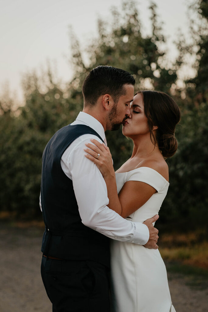 the bride and groom kissing in a grove of trees at The Orchard Hood River. 