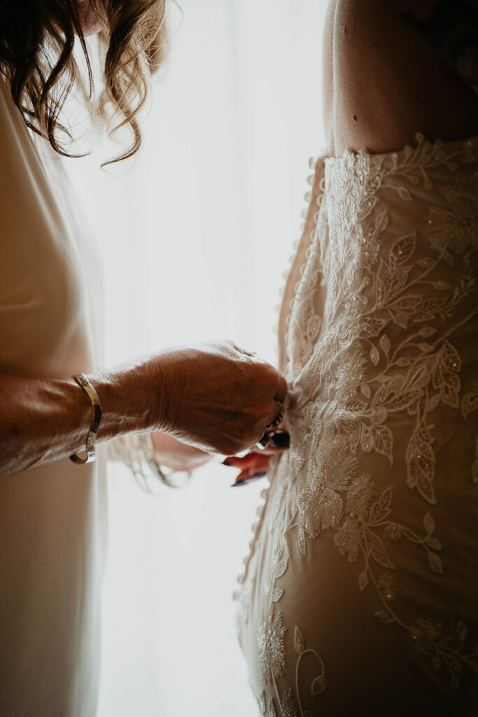 The bride getting her dress sipped up.