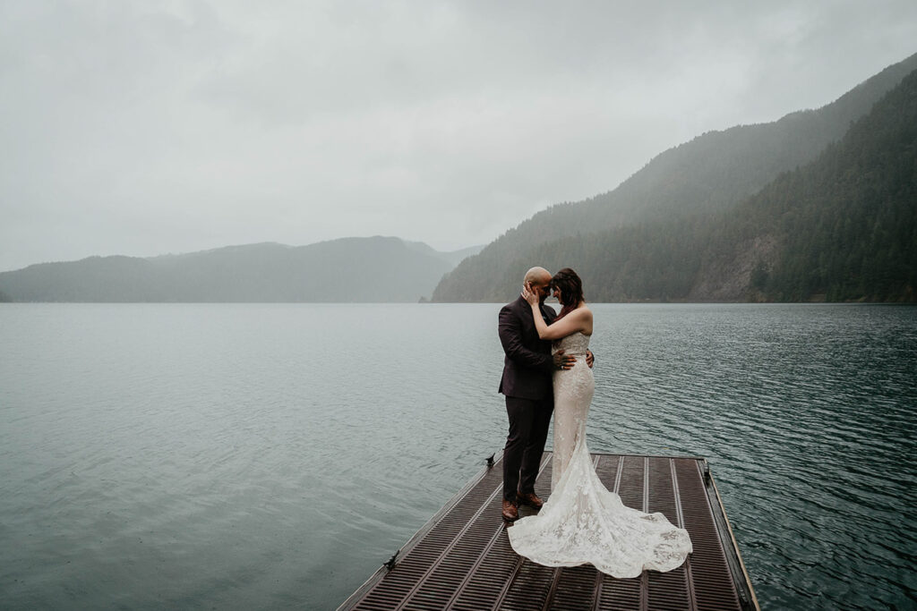 The newlyweds holding each other on a dock at Lake Crescent during their elopement. 