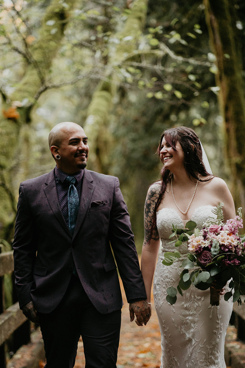 the newlyweds walking on a bridge in the forest. 