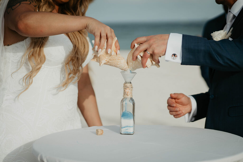 The bride and groom mixing sand together as a part of their Mexico destination wedding ceremony. 