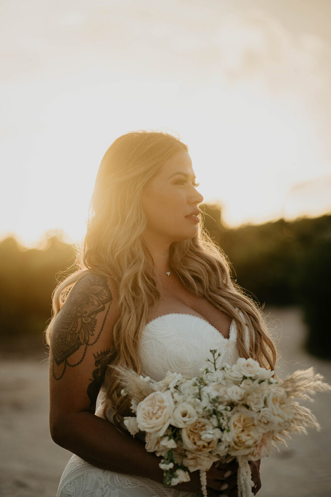 The bride posing on the sand at sunset during their Mexico destination wedding