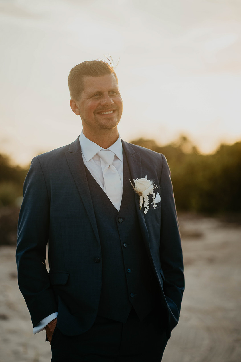 The groom posing on the sand at sunset during their Mexico destination wedding. 