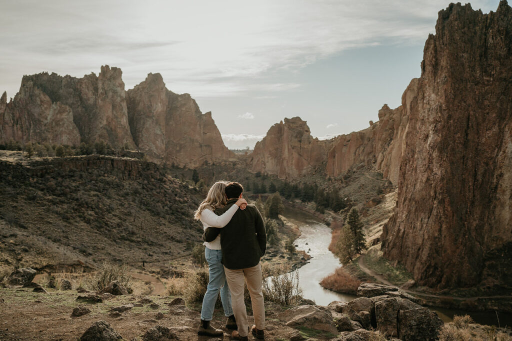 A couple embracing each other with an expansive view of Smith Rock State Park. 