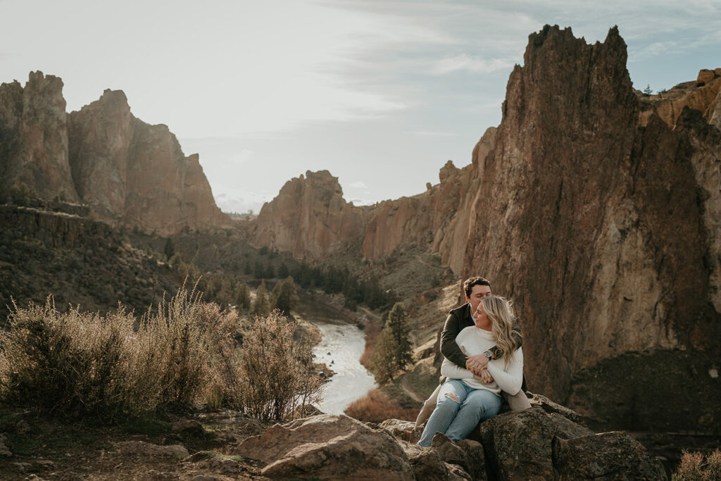 The engaged couple holding each other with smith rock in the background during their engagement session. 