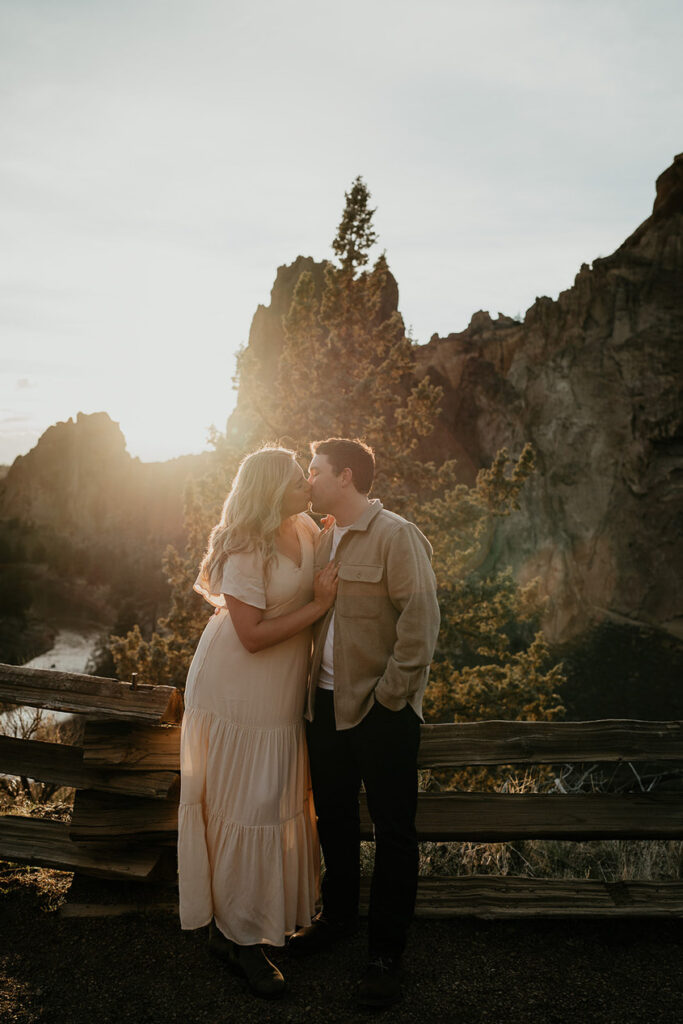 A couple kissing with a river and spires in the background. 