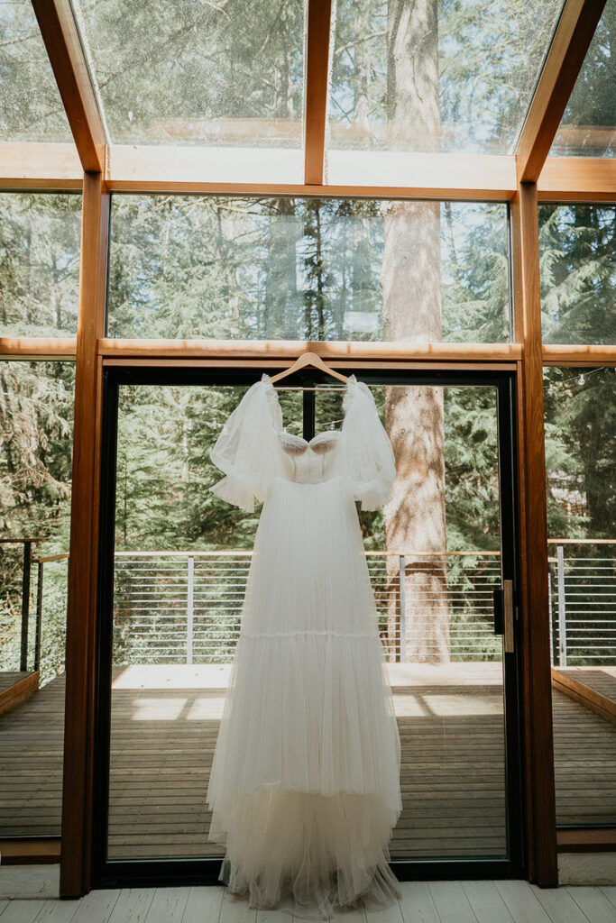 the brides dress hanging in front of a window. 