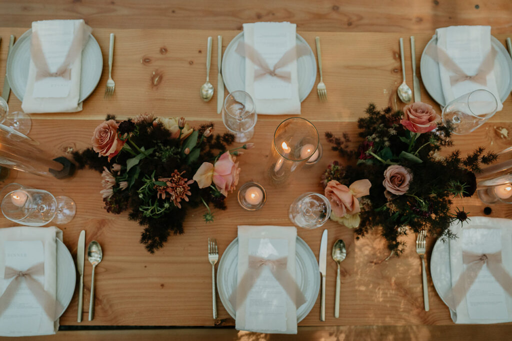 dinner plates, utensils, wine glasses, and table decorations at a green house at The Woodlands house venue. 