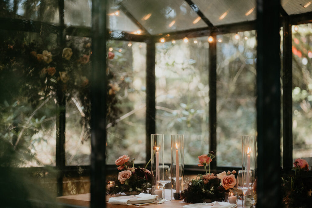 dinner plates, utensils, wine glasses, and table decorations at a green house at The Woodlands house venue. 