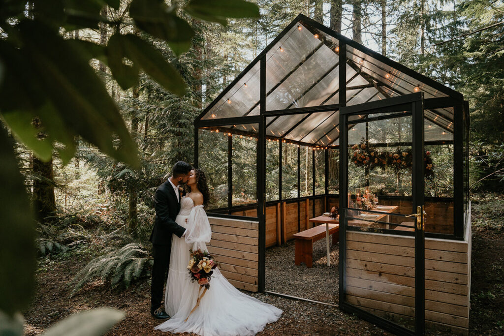 The newlyweds kissing in front on the greenhouse at the Woodlands House venue. 