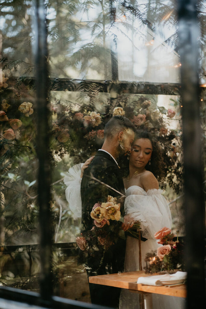 The bride and groom holding each other inside the greenhouse at The Woodlands House venue. 