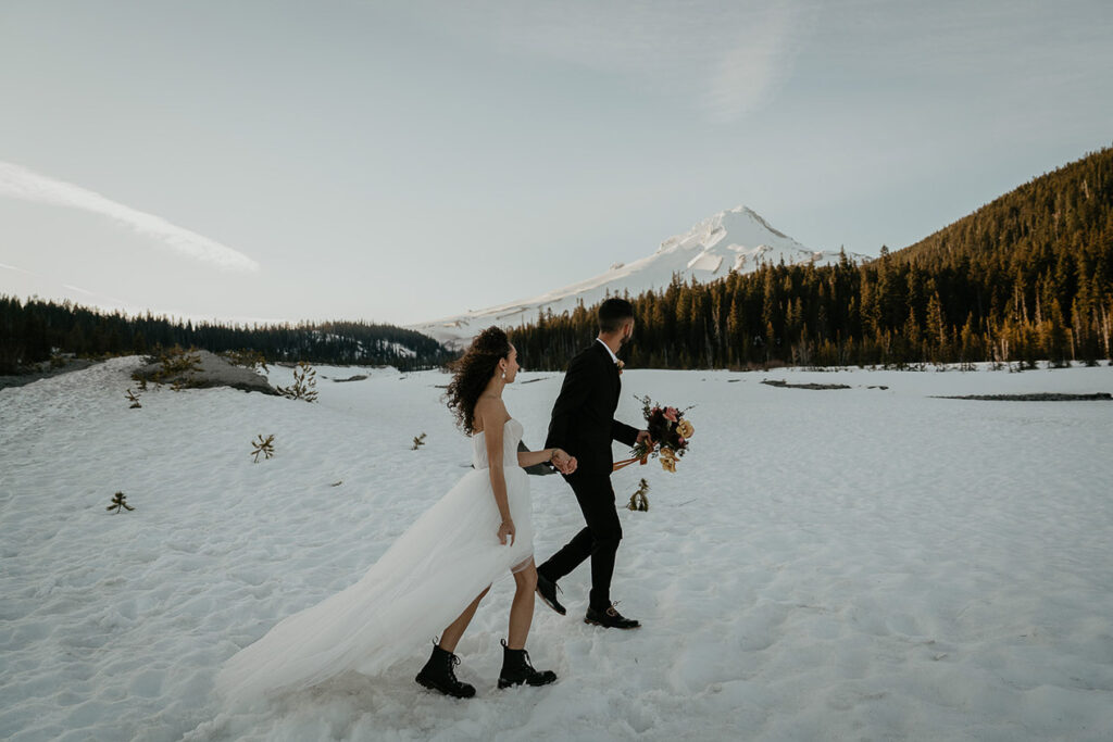 the newlyweds walking in the snow with Mt Hood in the background. 