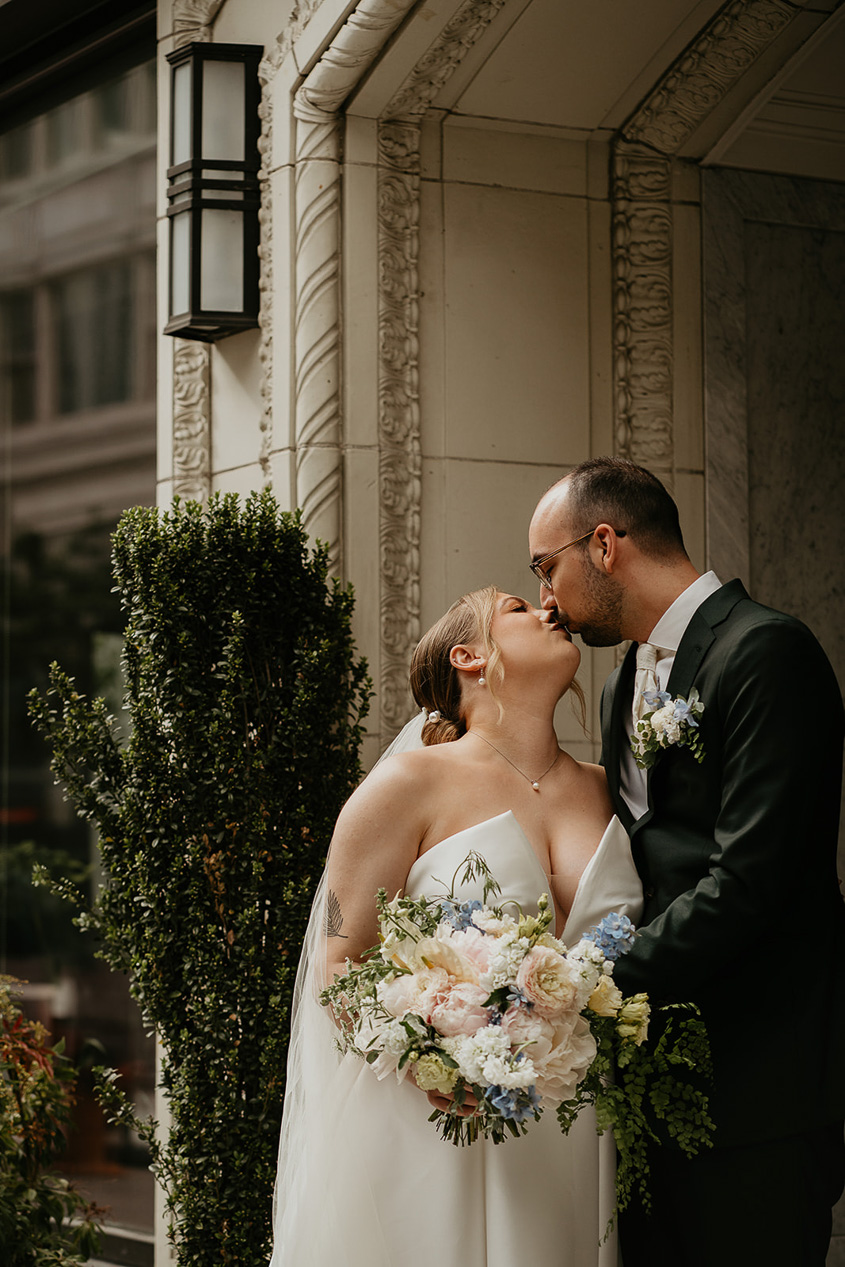 the bride and groom kissing while exploring downtown Portland. 