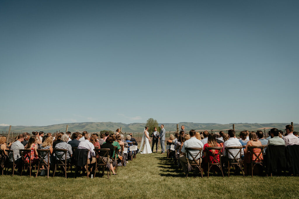 the bride and groom standing at the altar with their wedding guests watching. 