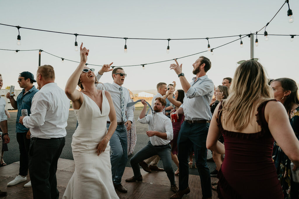 the bride, groom, and wedding guests dancing. 