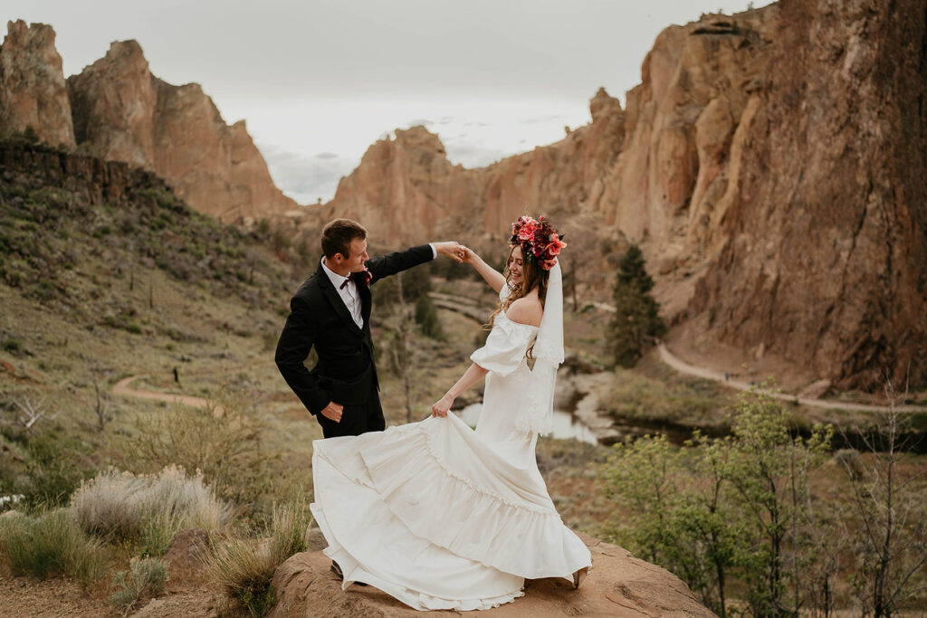 A couple holding hands with mountains and a valley in the background. 